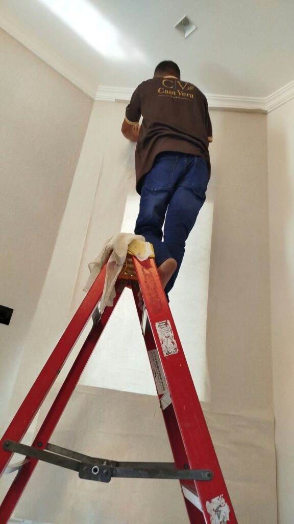 Wallpaper installer working on a tall wall