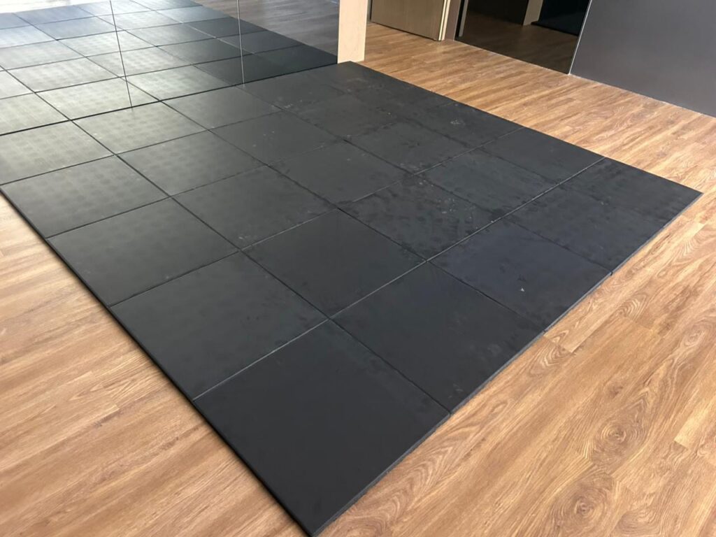 Black rubber gym floor tiles installed in a home gym